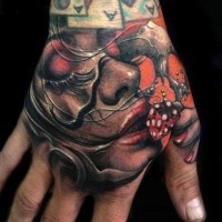 Realistisch aussehendes farbigesFrauenporträt Tattoo an der Hand mit rotem Würfel