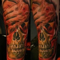 Realistisch aussehendes farbiges Unterarm Tattoo des menschlichen Schädels mit verletzter Hand