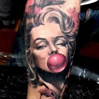 Realistic looking colored Merlin Monroe with gum balloon tattoo on forearm