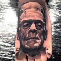 Realistisch aussehendes detailliertes schwarzweißes Frankenstein Monster Gesicht Tattoo am Fuß