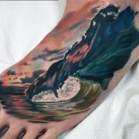 Realistic looking multicolored big ocean wave tattoo on foot