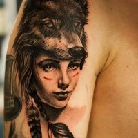 Realistic looking shoulder tattoo of woman with wolf skin