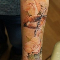 Tatuaje en el antebrazo, pájaro en la rama y flores delicadas