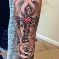 Realistic religious winged gray-ink cross with red heart and rose tattoo on forearm