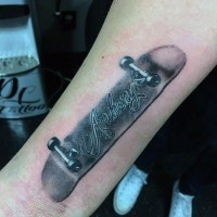 Realistisches Skateboard Gedenk Tattoo mit dem Namen Schriftzug am Arm