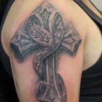 Tatuaje en el brazo, cruz de piedra con serpiente que silba