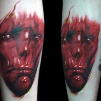 Red colored creepy looking arm tattoo of demonic face