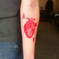 Red ink heart and letters forearm tattoo