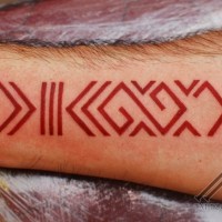 Red latin symbol forearm tattoo