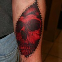 Red skull beneath skin forearm tattoo