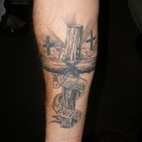 Religious christian gray-ink wooden cross with lettering tattoo on forearm