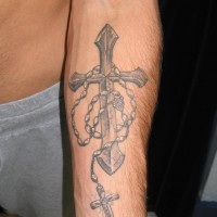 Religious gray-ink cross with beads tattoo on forearm