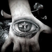 Religious Jesus Christ crucifix in human eye detailed tattoo on hand