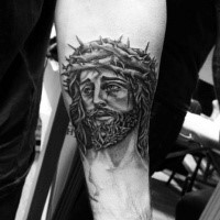 Religious Jesus Christ portrait in crown of thorns tattoo on forearm