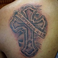Tatuaje en el hombro, cruz grande agrietado de piedra y cinta con inscripción