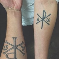 Tatuaje en el antebrazo,
 monograma de Cristo, tinta negra