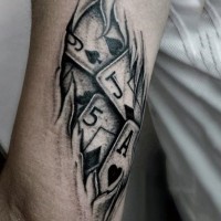 Ripped skin style black and white playing cards tattoo on arm