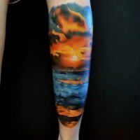 romantico disegno colorato oceano su tramonto tatuaggio su gamba