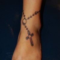 Tatuaje de cabena con cruz en el tobillo