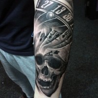 Tatuaje en el antebrazo, cráneo humano con naipes y ruleta