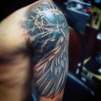 Sharp crown of thorns and feather wing religious shoulder tattoo in realistic style