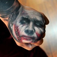 Sharp designed colored sad Joker face tattoo on fist