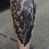 Tatuaje en negro y blanco el cráneo en el humo en la pierna