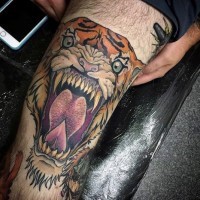 Tatuaje en el muslo, tigre furioso con colmillos afilados