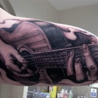 Tatuaje en el brazo, manos tiernos con guitarra acústica