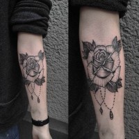 Tatuaje en el antebrazo,
rosa simple con colgante, colores negro blanco