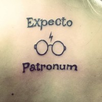 Simple black ink Harry Potter the most famous spell lettering tattoo on back with glasses