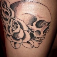 Einfacher schwarzer menschlicher Schädel mit Rosen Tattoo am Oberschenkel