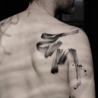 Simple black ink ribbon shaped tattoo on shoulder area