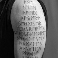 Simple black ink shoulder tattoo of ancient lettering