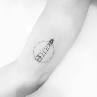 Simple design small size lighthouse in circle tattoo on biceps