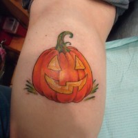 Simple designed and colored little Halloween pumpkin tattoo on leg