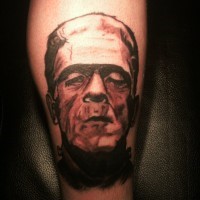 Simple designed black and white Frankenstein monster portrait tattoo on leg