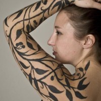 Tatuaje en el brazo completo,
rama con hojas y bayas, tinta negra