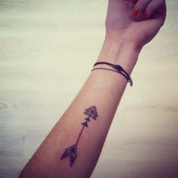 Simple gray-ink arrow tattoo on forearm