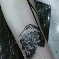 Simple homemade like black ink skull with note tattoo on arm