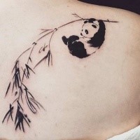 Simple little black ink scapular tattoo of little panda with olive branch