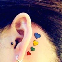 Tatuaje detrás de la oreja, corazoncitos diminutos de varios colores