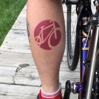 Simple red colored bicycle shaped emblem tattoo on leg