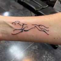 Simple tiny black ink dog shaped tattoo on wrist