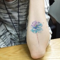 Simple tiny watercolor like colored flower tattoo on forearm