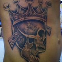 Tatuaje en el costado, cráneo sonriente en la corona