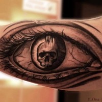 Skull in eye pupil tattoo on arm
