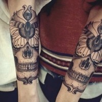 Tatuaggio su due bracci i teschi stilizzati