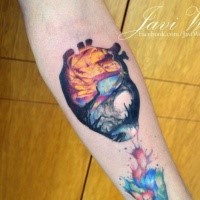 Smal new school style colored forearm tattoo of human heart stylized with mystical forest