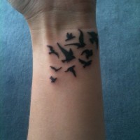 Tatuaje en la muñeca, bandada de aves sencillas